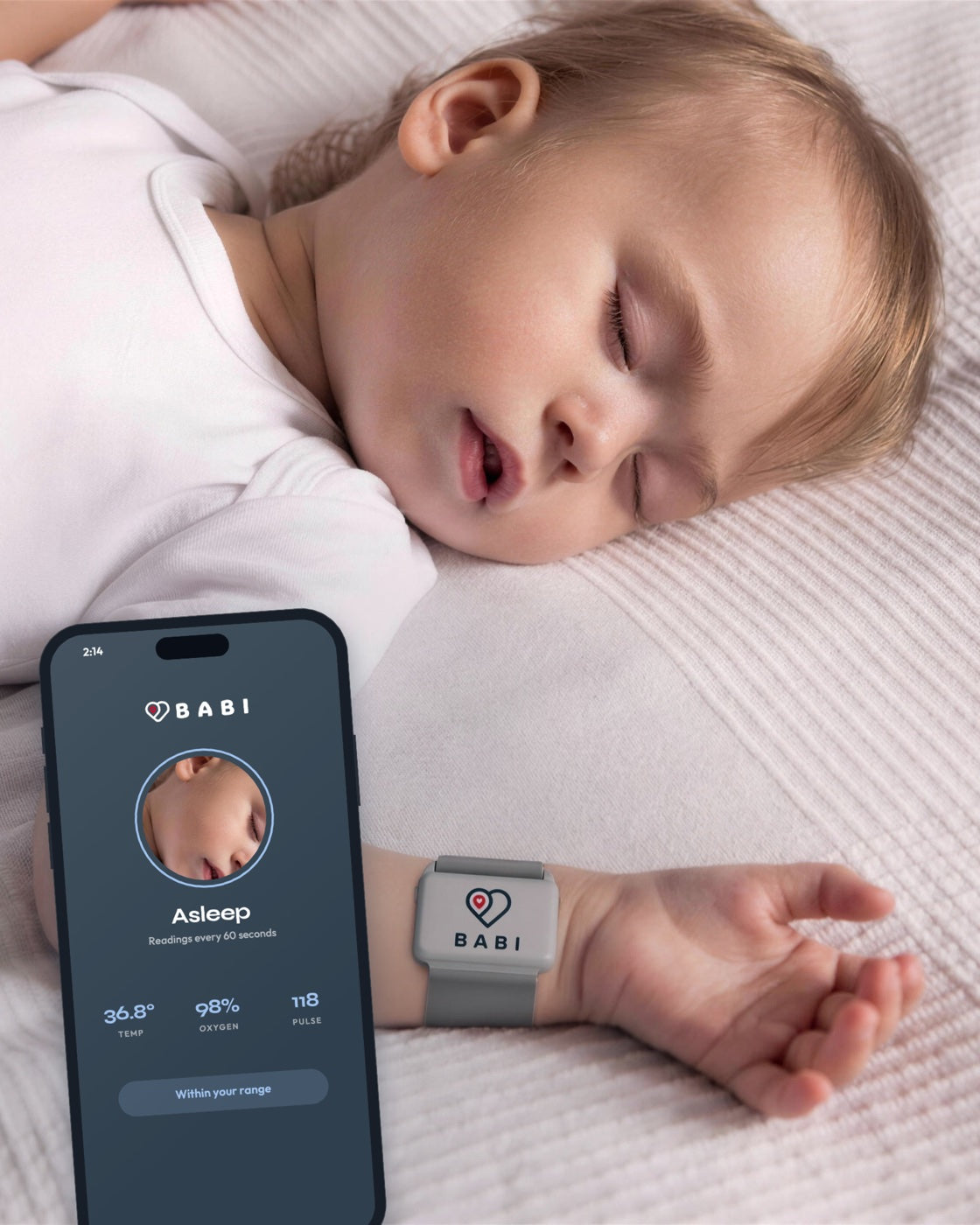 A baby asleep wearing Babi Angel, and parents asleep with the phone on its stand beside them